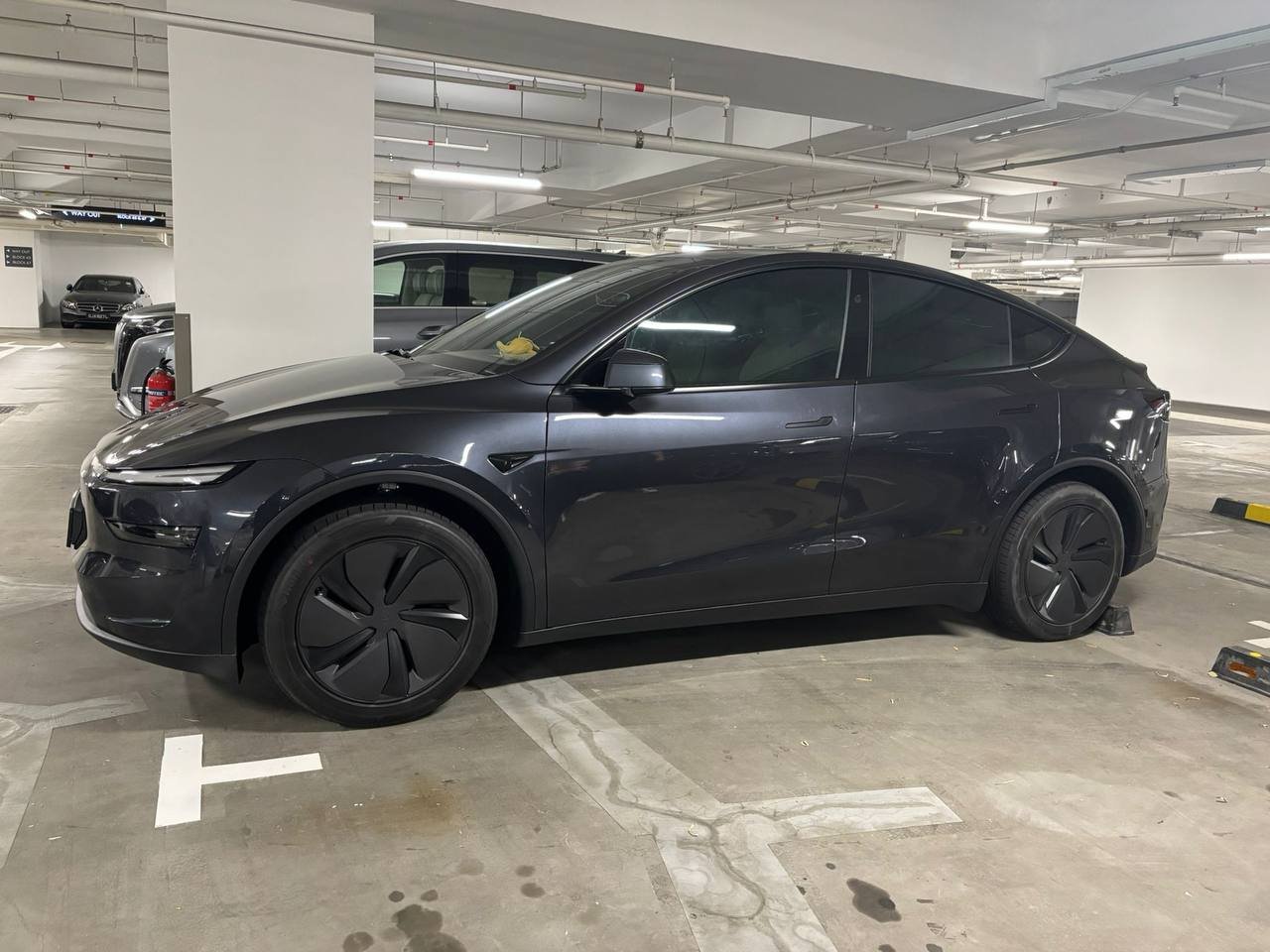 Grey Tesla Model Y, side profile, parked in a garage